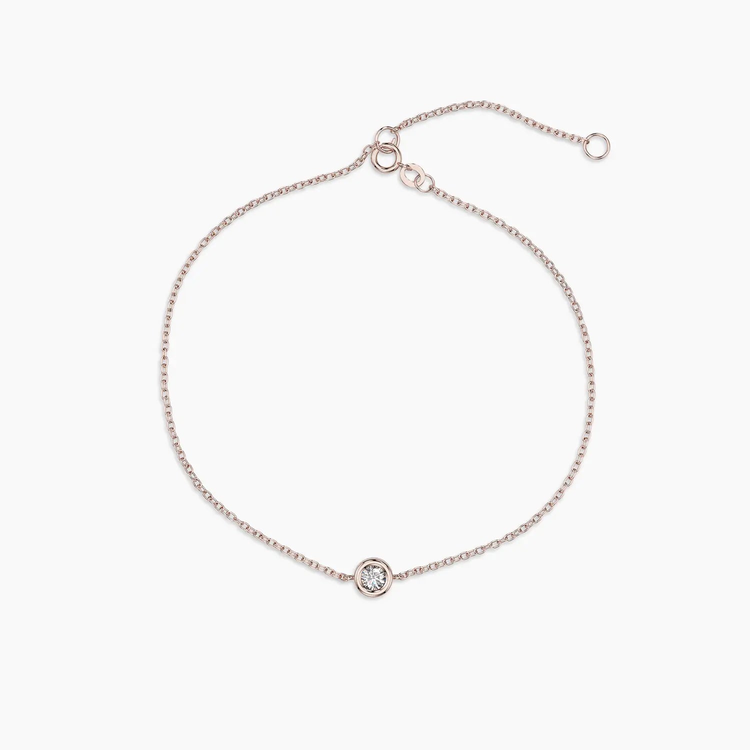 Delicate bracelet in rose gold showcasing a bezel-set diamond at the center, styled with an adjustable chain.

