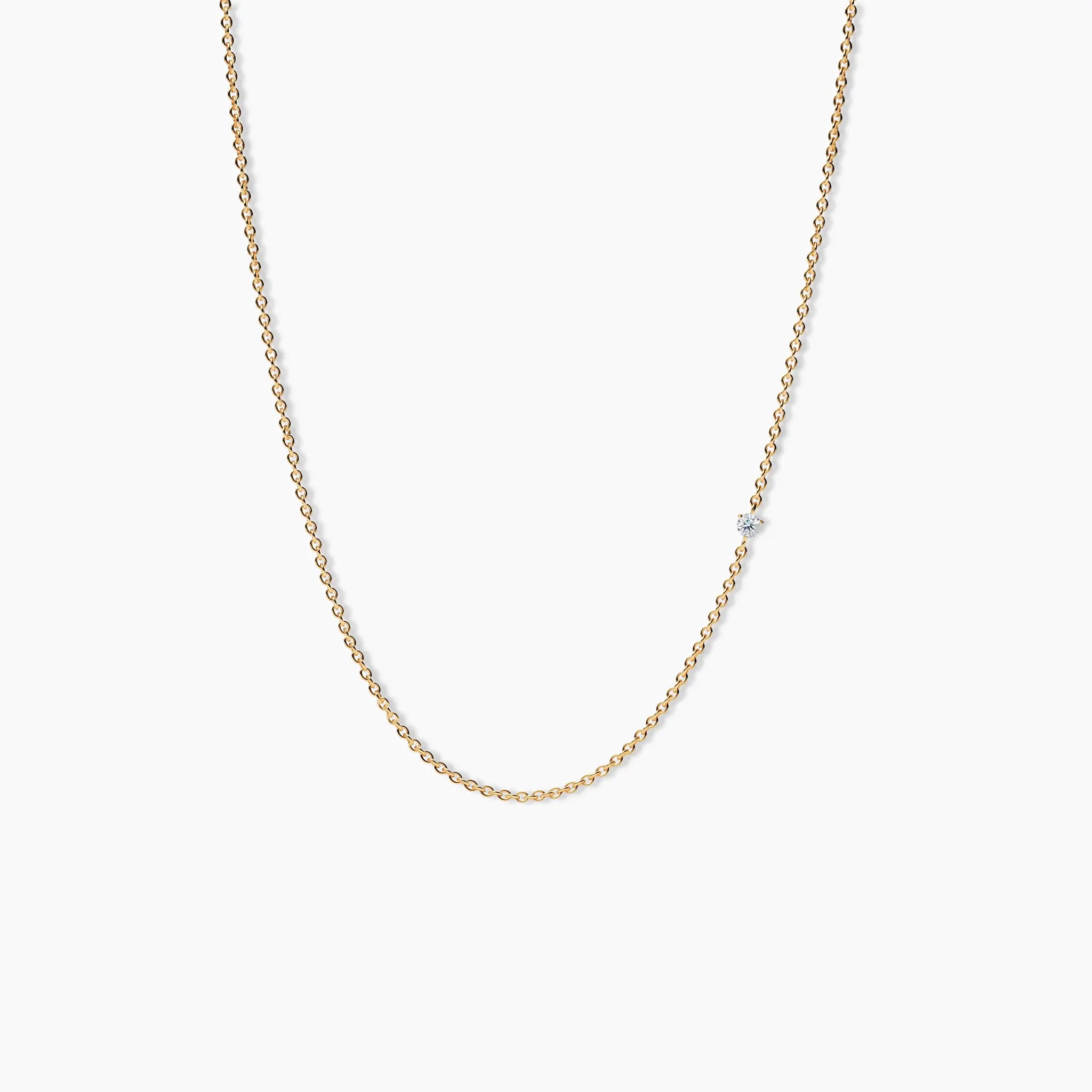 Product shot of the diamond choker necklace laid flat in a gentle curve, showing the delicate 14k yellow gold chain with a centered small diamond.
